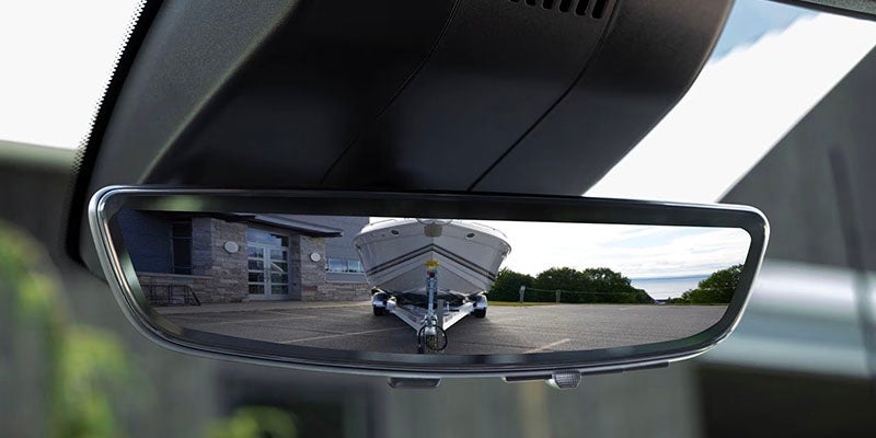 Rear view mirror view of the 2026 Chevrolet Silverado 1500 towing a boat, demonstrating its capability and precision for outdoor adventures near Buellton, CA.
